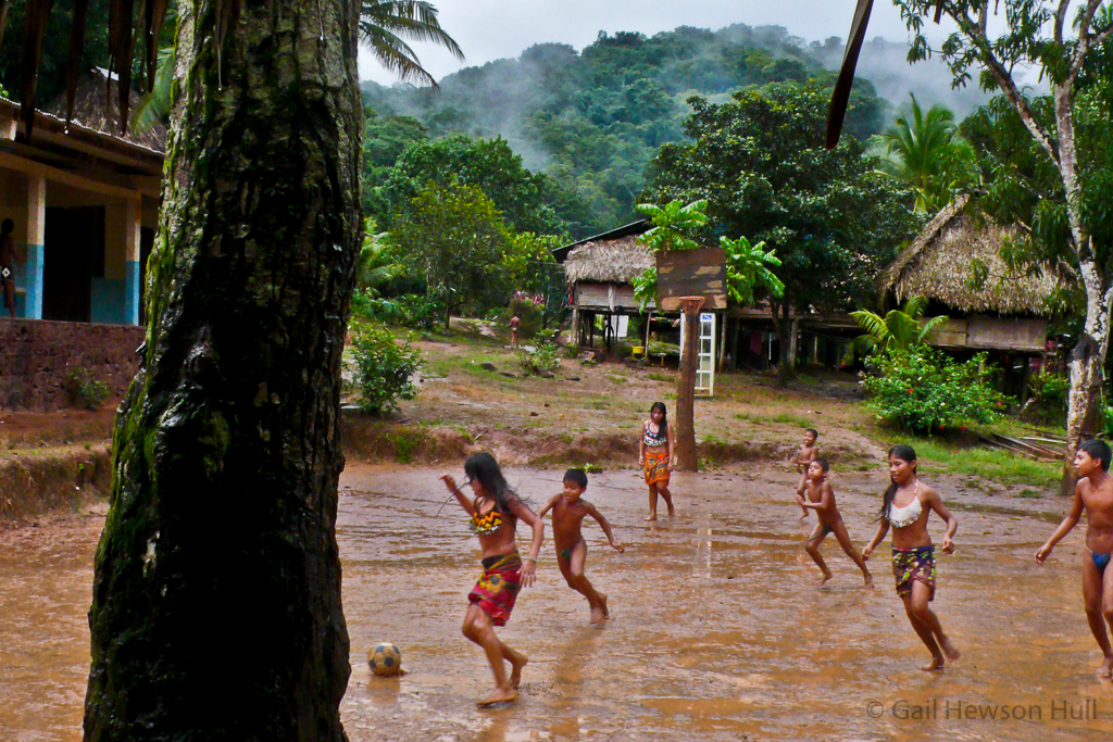 Children play soccer in the rain.